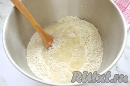 200 миллилитров воды подогреваем до температуры 38-40 градусов. Вливаем тёплую воду и растительное масло в центр мучной смеси.