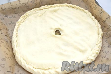 Вторую часть теста тоже раскатываем в лепёшку диаметром 29 сантиметров, выкладываем поверх лепёшки с начинкой из картошки и грибов. Скрепляем края, формируя закрытый осетинский пирог, в центре делаем отверстие.