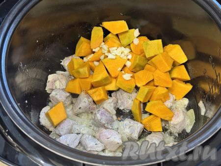 К свинине, обжаренной с тыквой, добавить кусочки тыквы и мелко нарезанный чеснок. 