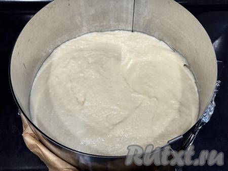 Тесто для заливного пирога должно получиться однородным, в меру густым, напоминающим сметану средней жирности. Если тесто получилось жидковатым, можно добавить ещё немного муки. Количество муки, которое придётся добавить в тесто, зависит от размера яйца, от жирности сметаны и сливочного масла. Разъёмную форму для выпечки (я взяла форму диаметром 22 сантиметра) смазать растительным маслом. Разделить тесто на 2 части, одну часть выложить в форму для выпечки. В качестве формы для выпечки я использовала кулинарное кольцо, сформировав дно из пергаментной бумаги и фольги, сложенных в несколько слоёв. Получившуюся форму поставила на противень и после этого выложила одну часть теста.