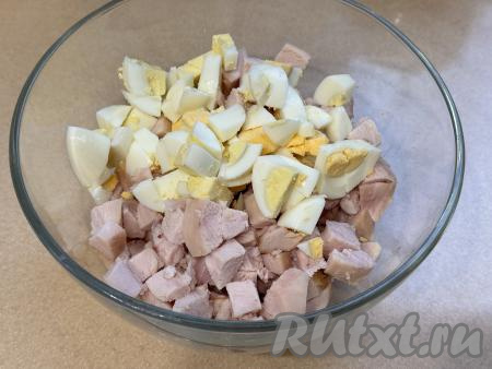 В миску с курицей добавить варёные яйца, нарезанные на средние кубики. 