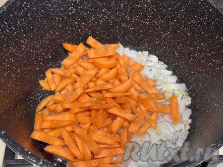 Обжарить лук на среднем огне в течение 4-5 минут (до прозрачности), иногда помешивая, затем добавить морковку, нарезанную на достаточно тонкие брусочки, сразу перемешать овощи.