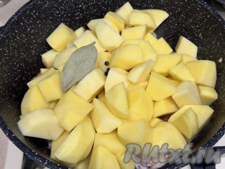 Картофель нарезать на средние кусочки и вместе с лавровым листом добавить в сковороду к обжаренной курице с овощами, всыпать горошины чёрного перца.