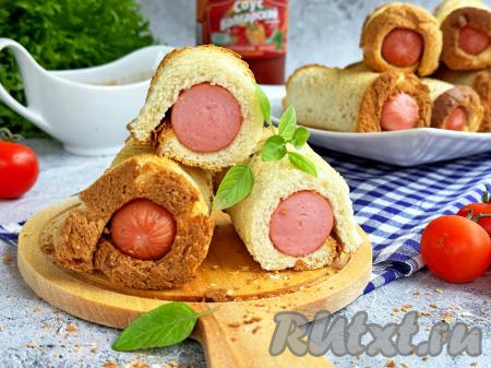 Аппетитные, вкусные сосиски в тостовом хлебе достать из духовки, переложить на тарелку и, дополнив, по желанию, соусом, подать к столу.