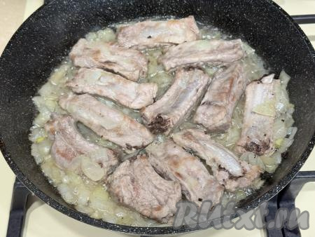 Обжарить рёбра с луком в течение 5 минут (до прозрачности лука), иногда перемешивая, на среднем огне. 