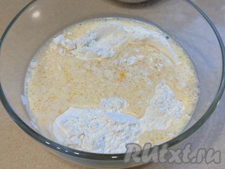 В получившуюся молочно-яичную смесь всыпать соду и 250 грамм просеянной муки, перемешать тесто столовой ложкой, а как только оно начнёт собираться в ком, продолжить замешивать его руками, всыпая по мере необходимости оставшуюся муку, тщательно  вмешивая её. 