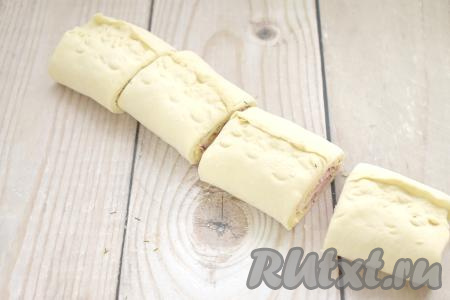 Скрепляем край теста. Нарезаем получившийся рулет с колбасой и сыром на 4 равных части.