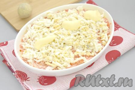 1 варёный яичный желток я оставила для украшения салата. Оставшееся яйцо и яичный белок натираем на крупной тёрке, выкладываем следующим слоем. Немного солим яичный слой и смазываем его майонезом.