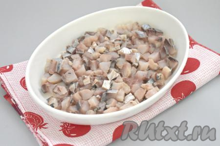 Филе солёной сельди нарезаем на небольшие кубики, равномерно выкладываем первым слоем в подходящий салатник.