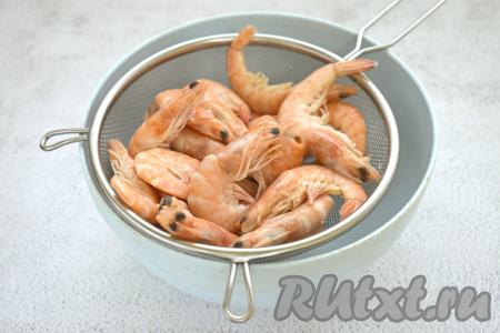 Замороженные креветки ополаскиваем холодной водой, выкладываем в сито (или в дуршлаг). Ставим сито (или дуршлаг) поверх миски, оставляем креветки размораживаться при комнатной температуре.