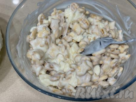 В миску с печеньем "Рыбки" добавить сметанный крем, смешанный с кусочками банана, перемешать массу столовой ложкой, равномерно покрывая всё печенье кремом. 