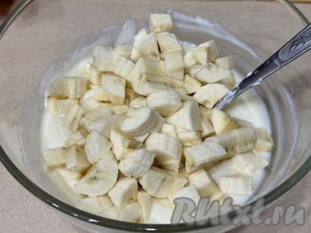 В миску со сметанным кремом добавить кусочки банана, хорошо перемешать. 