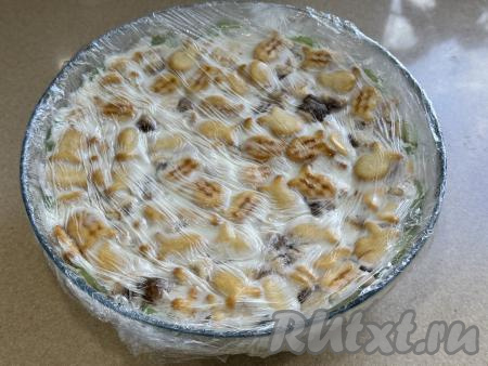 Поставить миску с тортом из печенья "Рыбки" с бананом и киви в холодильник на ночь. На следующий день убрать плёнку, покрывающую торт сверху.