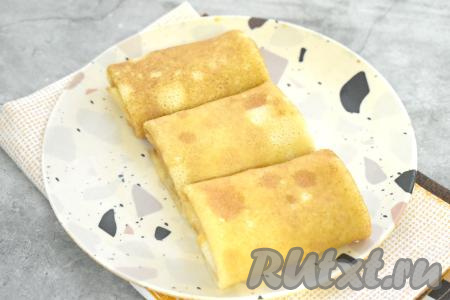 Подворачиваем боковые стороны блина на начинку, в затем, начиная со стороны с начинкой из индейки, сворачиваем блинчик конвертиком. Постепенно фаршируем все блины. К столу их лучше подавать тёплыми. Если блинчики остыли, их можно прогреть в микроволновке, на сковороде или в духовке.