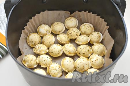 Застилаем чашу аэрогриля пергаментом. Выкладываем в чашу в один слой замороженные пельмени, смазываем их приготовленной смесью из масла и специй.