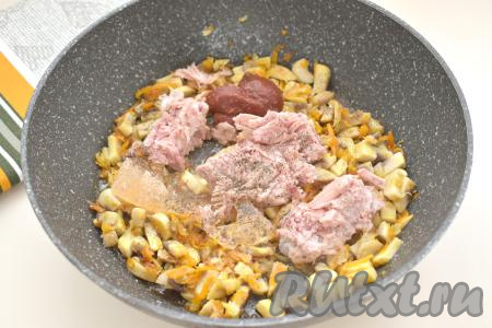 К шампиньонам, обжаренным с овощами, добавляем тушёнку (у меня - тушёнка из свинины), предварительно убрав жир, и томатную пасту, по вкусу солим и перчим, перемешиваем и готовим 5 минут, время от времени помешивая.