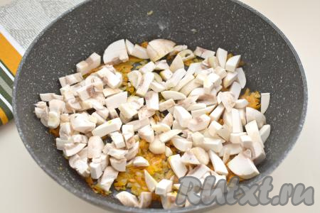 Шампиньоны моем, удаляя с грибов загрязнения. Нарезаем шампиньоны на небольшие кубики, выкладываем в сковороду с обжаренными овощами, перемешиваем. Обжариваем грибы с овощами 6-7 минут, периодически помешивая.