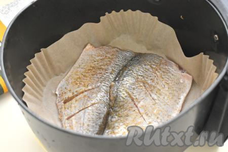 Чашу аэрогриля застилаем пергаментом, выкладываем в неё леща в специях, развернув рыбку, как книжку.