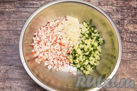 Репчатый лук очистить, промыть водой и нарезать как можно мельче, затем выложить в миску с салатом из крабовых палочек и огурцов.