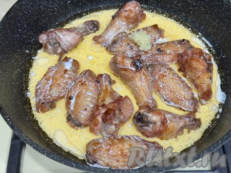 В сковороду с куриными крылышками, обжаренными до золотистого цвета, влить сливки, добавить пропущенные через пресс зубчики чеснока. Тщательно перемешать, покрывая все крылья сливками и равномерно распределяя чеснок.&nbsp;