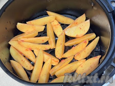 Выложить дольки картошки в чашу аэрогриля, желательно в один слой.