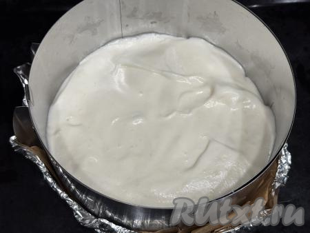 Переложить тесто в разъёмную форму диаметром 20 сантиметров. Разровнять поверхность теста лопаткой. Я использовала кулинарное кольцо без дна диаметром 20 сантиметров, а дно сформировала из пергаментной бумаги и фольги, сложенной в два слоя. Затем поставила получившуюся форму на противень и только после этого выложила тесто.