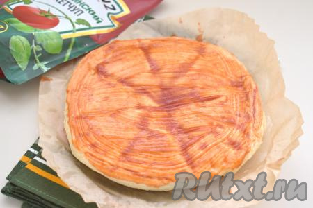 Так как нагрев в аэрогриле идёт только сверху, то нужно чтобы основа пиццы хорошо пропеклась. Аккуратно достаём пергамент с основой для пиццы из аэрогриля. Переворачиваем основу для пиццы и кладём на пергамент уже в перевёрнутом виде. Начинаем выкладывать начинку. Смазываем поверхность теста томатным соусом (или кетчупом).&nbsp;При желании можно перевернуть основу для пиццы прямо в чаше аэрогриле и сразу начинать выкладывать начинку. Но мне первый вариант кажется более удобным.