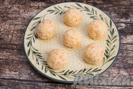 Руками, слегка смоченными водой, из получившейся массы сформировать шарики примерно вдвое больше по размеру, чем грецкий орех. Я сформировала 6 крабово-сырных закусочных шариков. Выложить шарики на плоскую тарелку.&nbsp;