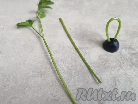 У веточек петрушки оставить только стебель. Согнуть стебель и вставить в половинку маслины - это будет крепление наших ёлочных шариков.