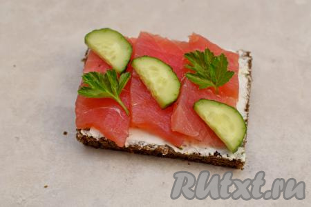 Огурец вымыть, нарезать на полукружочки. Выложить по три полукружочка огурца на бутерброды поверх рыбы. Я обычно выкладываю огурчики поверх рыбу по диагонали бутерброда. Бутерброды с солёным тунца и огурцом украсить зеленью (я украсила листьями петрушки).