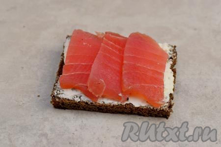 На каждый кусочек хлеба, смазанный творожным сыром, выложить несколько ломтиков тунца.