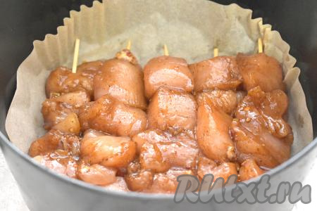 Замаринованные кусочки курицы нанизываем на деревянные шпажки. Чашу аэрогриля застилаем пергаментом или фольгой. Выкладываем куриный шашлык на шпажках в чашу аэрогриля в один слой.
