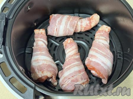 Куриные ножки, завёрнутые в бекон, выложить в чашу аэрогриля на решётку.