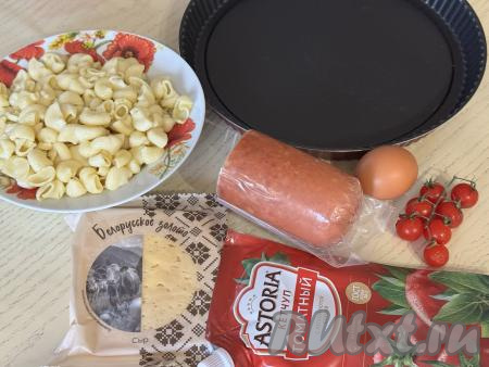 Подготовить продукты для приготовления пиццы из макарон в духовке. В кастрюле вскипятить достаточно большое количество подсоленной воды, выложить макароны, перемешать, дать закипеть. Уменьшить огонь, отварить макароны до готовности (на варку макарон может потребоваться от 7 до 14 минут, точное время варки смотрите на упаковке макаронных изделий, которые вы отвариваете). Сварившиеся макароны откинуть на дуршлаг, дать лишней воде стечь. Дать макаронам остыть. Для этого блюда можно взять и 350-400 грамм макарон, оставшихся с обеда или ужина. Для этого блюда можно взять макароны любой формы желательно среднего размера (например, рожки, перья, спиральки).