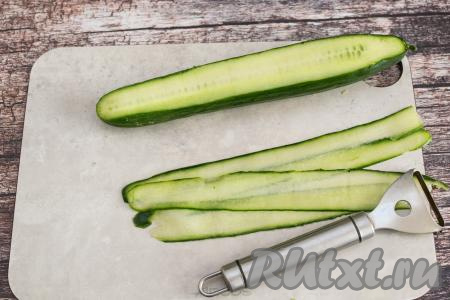 Длинный плотный огурец при помощи овощечистки нарезать вдоль на тонкие полоски.
