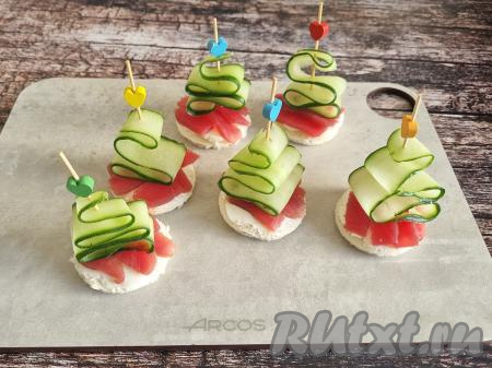 Надеть шпажки с ёлочками на бутерброды. Если шпажки очень длинные, тогда лишнюю часть шпажки отрежьте острыми ножницами.