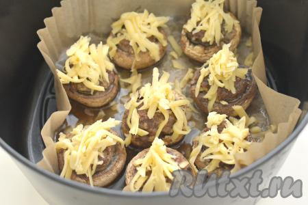 Фаршированные грибы посыпаем сыром, натёртым на крупной тёрке. Чашу возвращаем в аэрогриль, готовим&nbsp;шампиньоны, фаршированные фаршем и сыром, оставшиеся 5 минут. Сыр за это время расплавится, образуя аппетитную корочку.