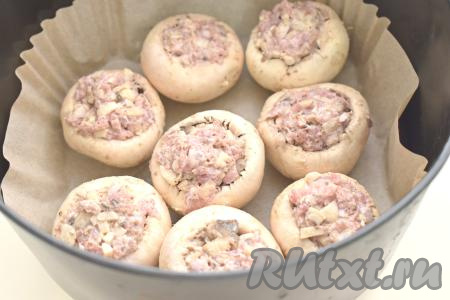 Чашу аэрогриля застилаем пергаментом, выкладываем шампиньоны, фаршированные&nbsp; фаршем.