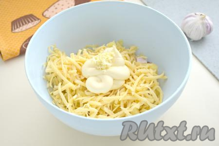 В салат из копчёной курицы, ананасов и сыров добавляем пропущенный через пресс чеснок и майонез.