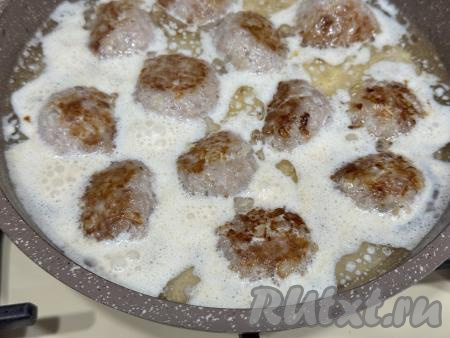 В сковороду с обжаренными фрикадельками влить сливки.&nbsp;