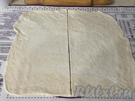 "Отдохнувшее" тесто выложить на рабочую поверхность, присыпанную мукой, и раскатать в пласт толщиной около 3 миллиметров. Разрезать получившийся тонкий пласт на 2 равные части.