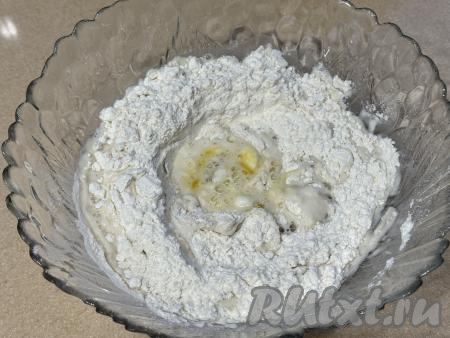 Влить 50 миллилитров воды комнатной температуры, перемешать столовой ложкой. Затем частями начать подливать оставшуюся воду комнатной температуры, каждый раз хорошо вмешивая её. Вначале перемешивать тесто столовой ложкой, а после того как оно начнёт комковаться, продолжать замешивать его руками.