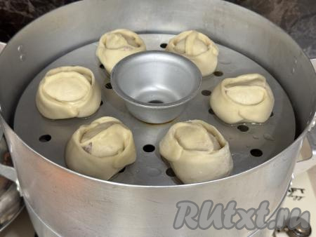 В мантоварку влить воду, поставить на достаточно сильный огонь. Дать воде закипеть, уменьшить огонь. Установить в мантоварку поддоны с мантами с начинкой из свинины и лука.