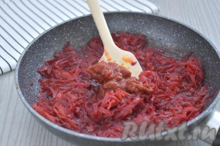 Затем из кастрюли, в которой варятся капуста с картошкой, берём 100-150 миллилитров воды, вливаем в сковороду с обжаренными овощами, перемешиваем. Даём воде в сковороде закипеть, уменьшаем огонь, тушим овощи под крышкой минут 5-10 (до мягкости свеклы и моркови), не забывая периодически перемешивать. Когда овощи станут достаточно мягкими, добавляем в сковороду томатную пасту, перемешиваем и тушим ещё 5 минут, иногда помешивая, убираем с огня.