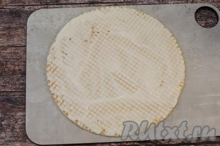 Смазать вафельный корж сверху примерно 4-5 столовыми ложками творожного крема, особенно хорошо нужно смазывать края коржа.