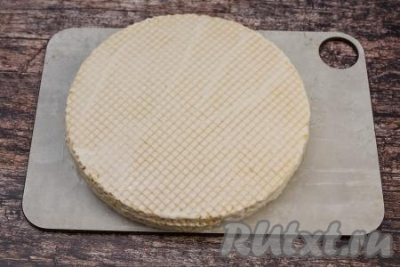 На смазанный корж выложить следующий вафельный корж, тоже смазать его сверху творожным кремом. Если есть повреждённые коржи, тогда их выложить в середину торта и смазать. Так, укладывая коржи и промазывая их кремом, собрать весь торт. Последний корж должен быть без повреждений, как и первый. Слегка прижать ладонью верхний корж. Смазать творожным кремом верх последнего коржа. Всего у меня были 8 вафельных коржей. Слегка промазать и бока торта оставшимся кремом. Торт из готовых вафельных коржей убрать на 3-4 часа в холодильник, чтобы он как следует пропитался. Я перед отправкой в холодильник торт накрываю сверху пластиковой крышкой для микроволновки.