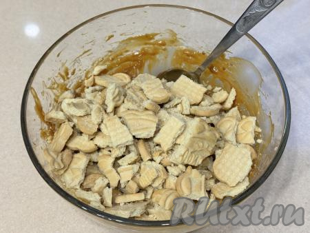 Добавить кусочки печенья в миску с кремом из сгущёнки и масла.