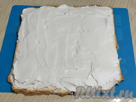 Немного крема сразу отложить в кулинарный мешок для украшения. Оставшийся крем выложить на остывший меренговый корж и равномерно распределить.