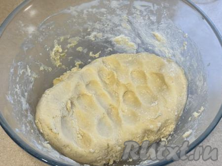 Вначале перемешивать песочное тесто столовой ложкой, а затем замесить руками нежное, пластичное тесто. При необходимости частями всыпать оставшуюся муку, каждый раз тщательно вмешивая её. Как только тесто перестанет липнуть к рукам, но будет мягким, значит больше муку добавлять не нужно. Долго песочное тесто вымешивать не нужно, достаточно просто собрать его в ком.