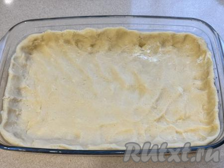 Разделить тесто на две равные части. Одну часть поместить в пакет и убрать в морозилку минут на 25-30. Вторую часть теста выложить в форму для выпечки (я выложила в прямоугольную форму размером 28 сантиметров на 18 сантиметров, но можно использовать и круглую форму). Распределить тесто по дну формы, сформировать невысокий бортик.&nbsp;
